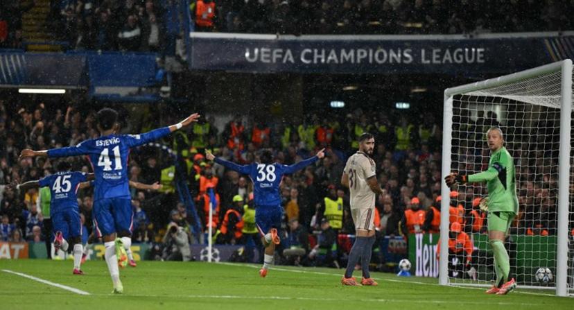Chelsea's Spanish striker #38 Marc Guiu (C) celebrates scoring the opening goal with team-mates as Ajax's Dutch goalkeeper #22 Remko Pasveer (R) reacts during the UEFA Champions League league-phase football match between Chelsea and Ajax at Stamford Bridge in London on October 22, 2025.  Glyn KIRK / AFP