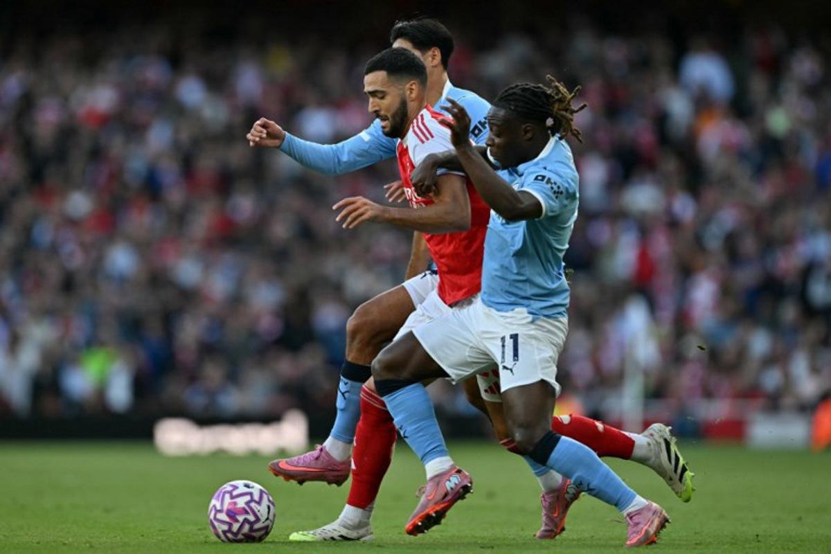 Arsenal's Spanish midfielder #23 Mikel Merino (C) vies with Manchester City's Dutch midfielder #04 Tijjani Reijnders (L) and Manchester City's Belgian midfielder #11 Jeremy Doku (R) during the English Premier League football match between Arsenal and Manchester City at the Emirates Stadium in London on September 21, 2025.   Glyn KIRK / AFP