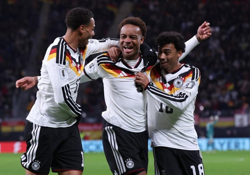 Germany's midfielder #09 Assan Ouedraogo (C) celebrates with Germany's midfielder #13 Felix Nmecha (L) and Germany's defender #18 Nathaniel Brown scoring his team's sixth goal during the FIFA World Cup 2026 European qualification Group A football match between Germany and Slovakia, at the Red Bull Arena in Leipzig, eastern Germany on November 17, 2025.  Ronny HARTMANN / AFP