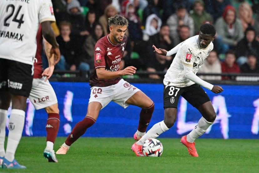 Metz's Algerian defender #22 Kevin Van Den Kerkhof (L) fights for the ball with Reims' Malian midfielder #87 Ange Martial Tia during the French L1 - L2 playoff first leg football match between FC Metz and Stade de Reims at the Saint-Symphorien Stadium in Metz, northeastern France, on May 21, 2025.   Jean-Christophe VERHAEGEN / AFP