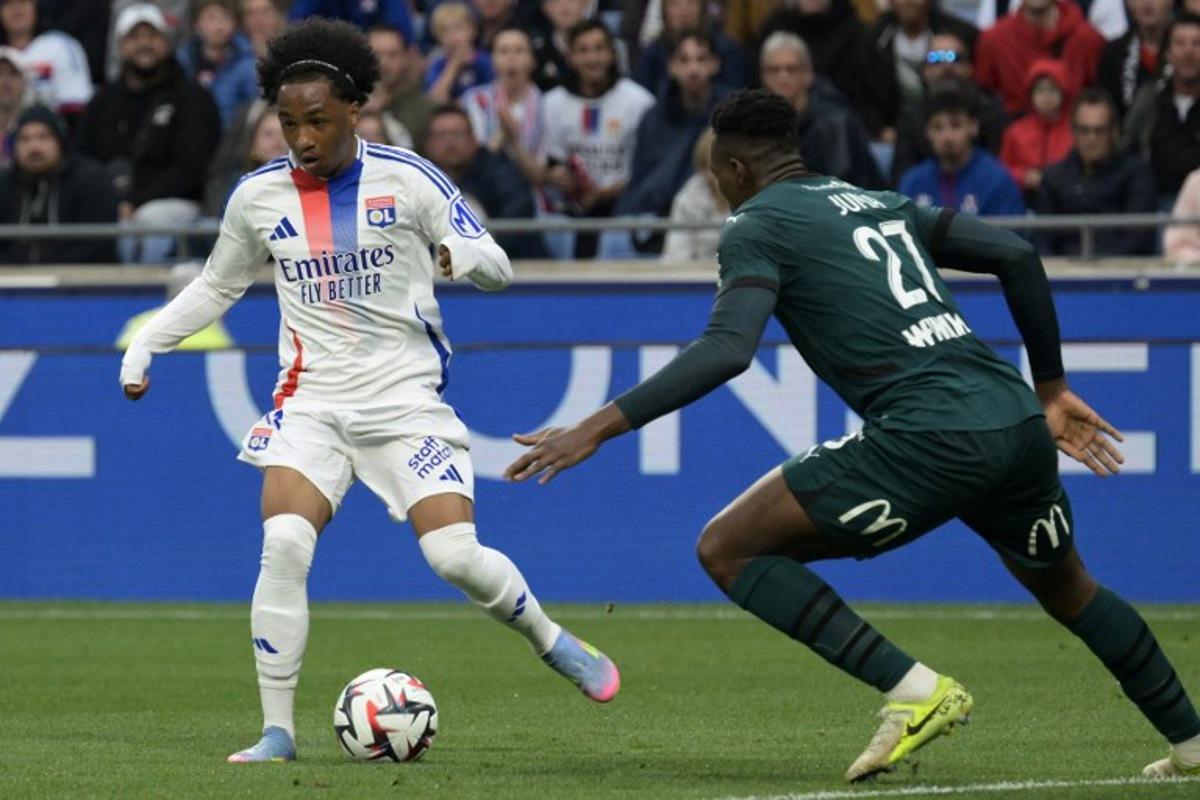 Lyon's Belgian forward #11 Malick Fofana (L) runs with the ball under pressure from Lens' Sierra Leonean defender #27 Juma Bah (R) during the French L1 football match between Olympique Lyonnais (OL) and RC Lens at Parc Olympique Lyonnais in Decines-Charpieu, central-eastern France, on May 4, 2025.  JEAN-PHILIPPE KSIAZEK / AFP
