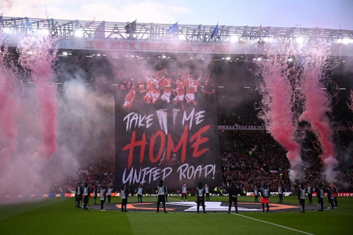 A Manchester United banner is unfurled in the stands as flares explode ahead of the UEFA Europa League semi final second leg football match between Manchester United and Athletic Club Bilbao at Old Trafford stadium in Manchester, north west England, on May 8, 2025.  Oli SCARFF / AFP