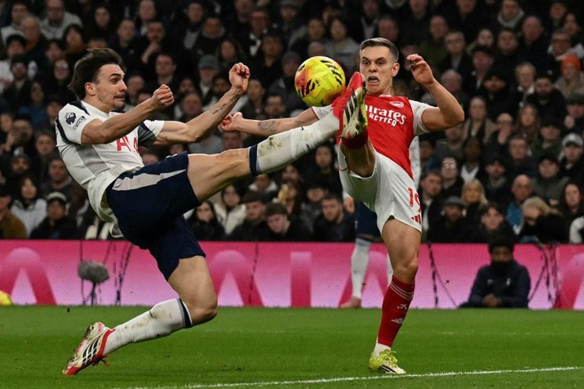 Arsenal's Belgian midfielder #19 Leandro Trossard (R) clashes with Tottenham Hotspur's Portugese midfielder #06 Joao Palhinha (L) during the English Premier League football match between Tottenham Hotspur and Arsenal at the Tottenham Hotspur Stadium in London, on February 22, 2026.  Glyn KIRK / AFP