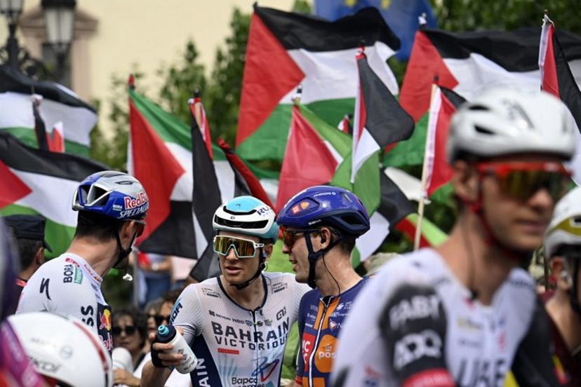 Pro-Palestinian protesters wave flags as riders await the start of the 15th stage of the Vuelta a Espana cycling tour, a 167 km race between A Veiga/Vegadeo and Monforte de Lemos, on September 7, 2025.    Miguel RIOPA / AFP