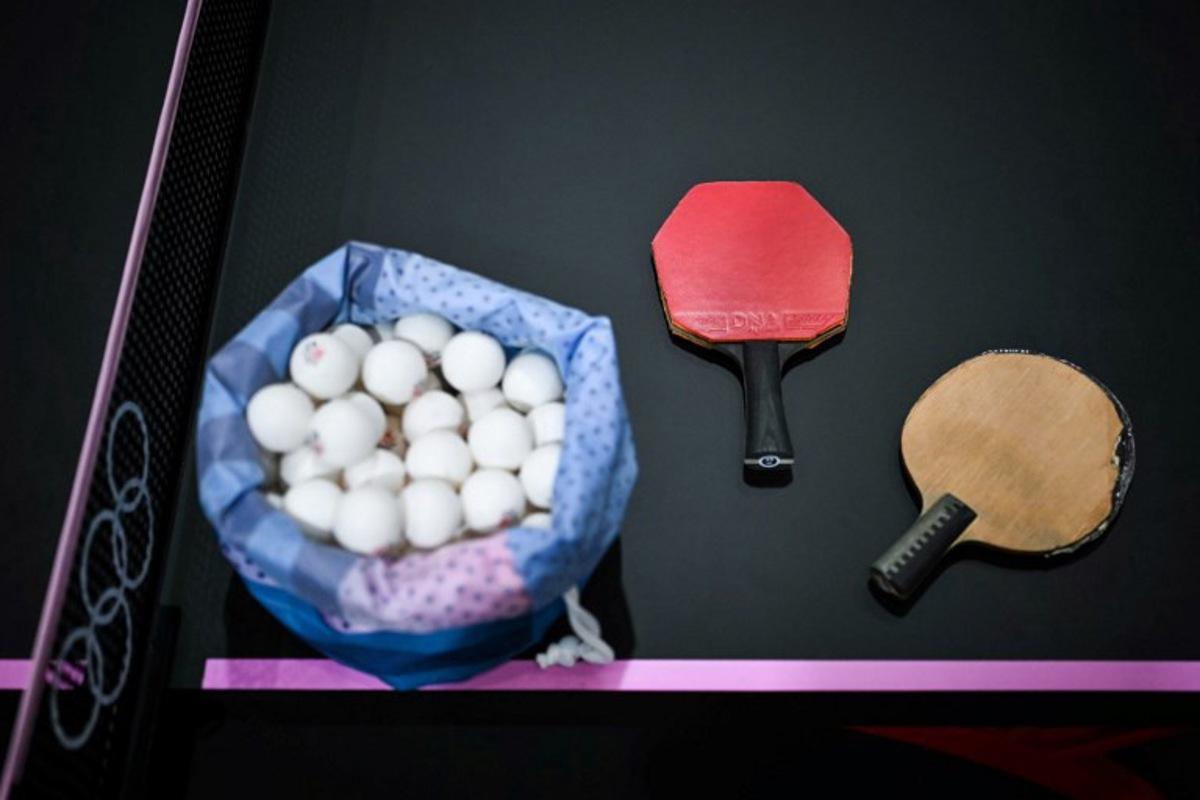 A plastic bag full of table tennis balls is pictured next to tennis table rackets during the training sessions on the third day of the table tennis competition at the Paris 2024 Olympic Games at the South Paris Arena in Paris on July 29, 2024.  Ben STANSALL / AFP