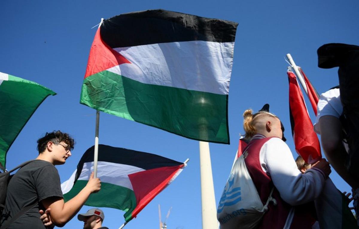 A participant displays a Palestinian flag during a demonstration under the motto 'Draw the red line with us: Together for Gaza!' in Berlin on September 27, 2025.   RALF HIRSCHBERGER / AFP