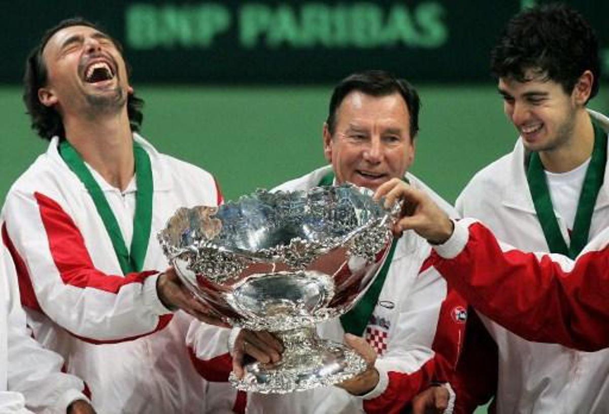 Croatian players Goran Ivanisevic (L), captain Nikola Pilic (C) and Mario Ancic hold the Davis Cup during the winner's ceremony following the Davis Cup finals between Slovakia and Croatia in Bratislava, 04 December 2005.  Croatia won 3-2.    AFP PHOTO/JOE KLAMAR