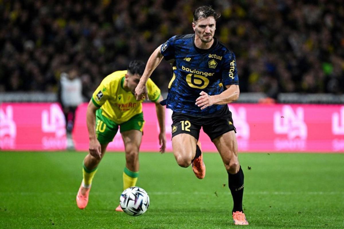 Lille's Belgian defender #12 Thomas Meunier (front) controls the ball past Nantes' French forward #10 Matthis Abline (rear L) during the French L1 football match between FC Nantes and Lille LOSC at the Stade de la Beaujoire-Louis Fonteneau in Nantes, western France, on October 19, 2025.  Sebastien Salom-Gomis / AFP