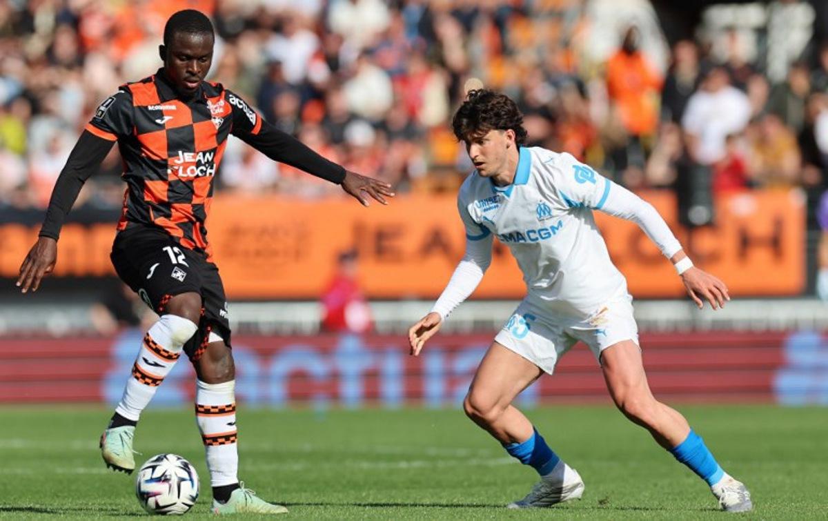 Lorient's Senegalese forward #12 Bamba Dieng (L) fights for the ball with Marseille's Argentinian defender #05 Leonardo Balerdi during the French L1 football match between FC Lorient and Olympique de Marseille at the Moustoir stadium in Lorient, western France on April 18, 2026.  Fred TANNEAU / AFP