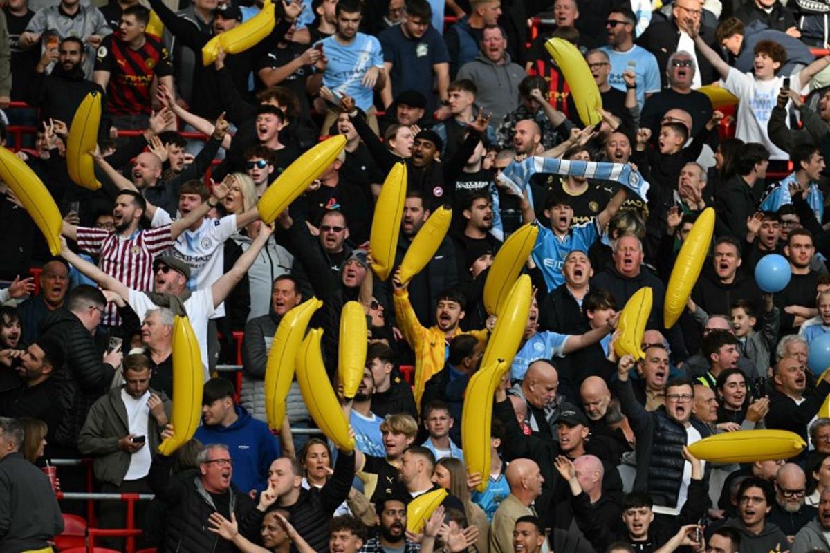 City fans wave inflatable bananas in the crowd ahead of the English Premier League football match between Liverpool and Manchester City at Anfield in Liverpool, north west England on October 11, 2026.  Paul ELLIS / AFP
