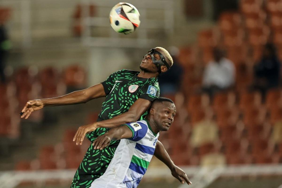 Nigeria's forward #9 Victor Osimhen jumps to head the ball as he is challenged by Lesotho's defender #2 Motlomelo Mkhwanazi during the FIFA World Cup 2026 Africa qualifiers group C match between Lesotho and Nigeria at the Peter Mokaba Stadium in Polokwane on October 10, 2025.  PHILL MAGAKOE / AFP