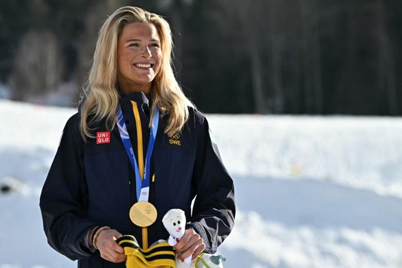 Gold medallist Sweden's Frida Karlsson celebrates on the podium for the women's cross country 10km + 10km skiathlon event of the Milano Cortina 2026 Winter Olympics at Tesero Cross-Country Skiing Stadium in Lago di Tesero (Val di Fiemme) on February 7, 2026.  Javier SORIANO / AFP