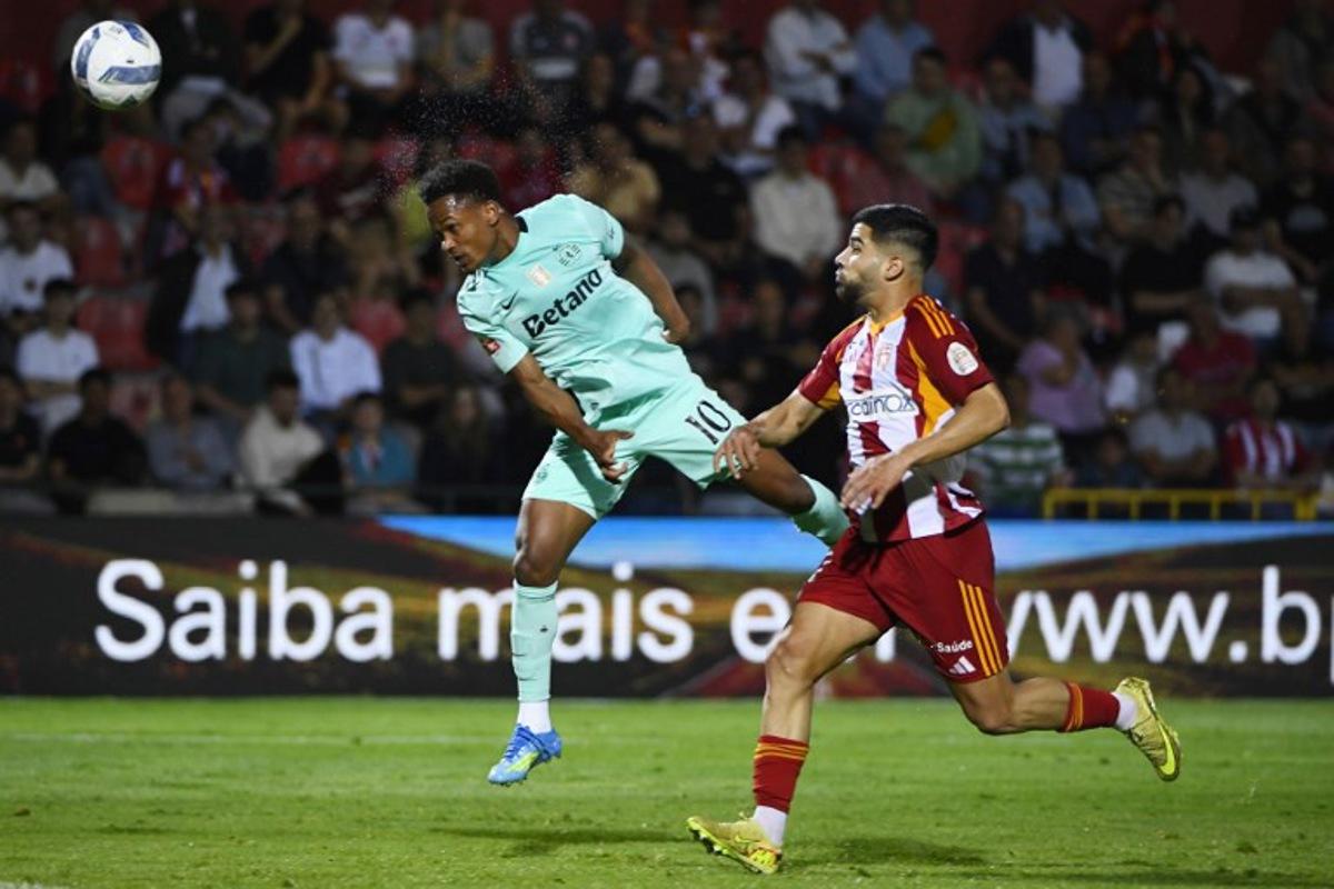 Sporting Lisbon's Mozambican forward #10 Geny Catamo heads the ball next to AVS' Nigerian forward #11 Tunde Akinsola during the Portuguese League football match between AVS Futebol SAD and Sporting CP at CD Aves stadium in Vila das Aves on April 26, 2026.  MIGUEL LEMOS / AFP