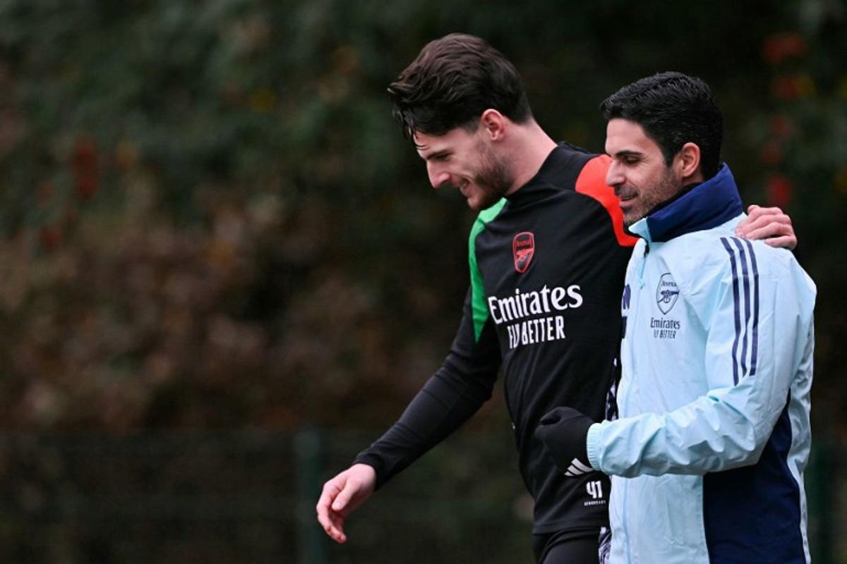 Arsenal's English midfielder #41 Declan Rice (L) and Arsenal's Spanish manager Mikel Arteta (R) speak together as they arrive to take part in a training session at the Arsenal Training centre in Shenley, north of London on December 10, 2024 on the eve of their UEFA Champions League football match against Monaco.  Glyn KIRK / AFP