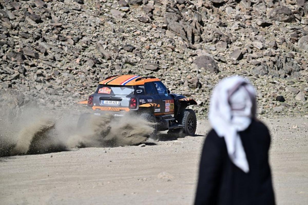 A local watches X-Raid Team Belgian driver Guillaume de Mevius and French co-driver Mathieu Baumel compete in the prologue, which determines the starting line-up for the first stage of the 48th edition of the Dakar Rally 2026, between Yanbu and Yanbu, Saudi Arabia, on January 3, 2026.  Giuseppe CACACE / AFP