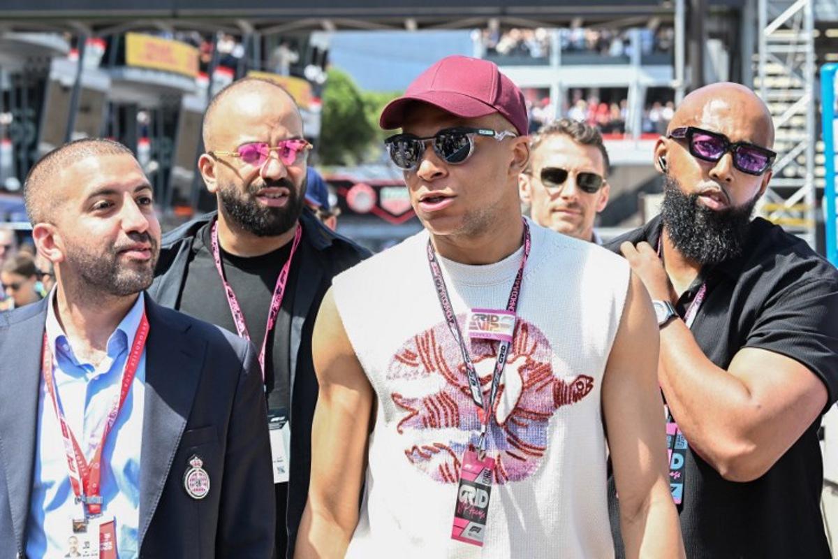 French footballer Kylian Mbappe (2R) walks in the pit lane ahead of the Formula One Monaco Grand Prix at the Circuit de Monaco, on May 25, 2025.  Gabriel BOUYS / POOL / AFP