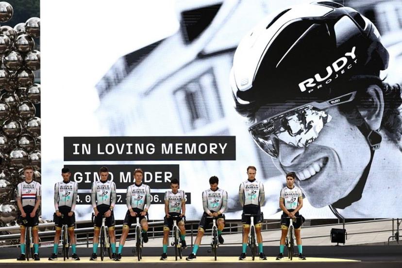Bahrain Victorious team riders pay tribute to their late teammate, Swiss rider Gino Mader (pictured on screen) during the official teams presentation near the Guggenheim Museum Bilbao, in Bilbao, northern Spain, on June 29, 2023, two days prior to the start of the 110th edition of the Tour de France cycling race.  Anne-Christine POUJOULAT / AFP