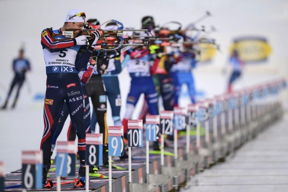Norway's Vetle Sjaastad Christiansen (L) fires his rifle during the men's 15km mass start event of the IBU Biathlon World Cup, in Le Grand Bornand, near Annecy, southeastern France, on December 21, 2025.  Olivier CHASSIGNOLE / AFP