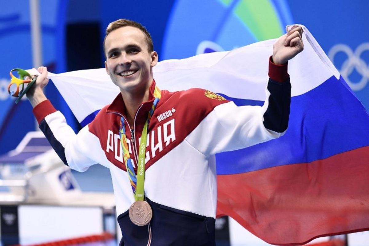 Russia's Anton Chupkov waves his national flag after he won the bronze medal in the Men's 200m Breaststroke Final during the swimming event at the Rio 2016 Olympic Games at the Olympic Aquatics Stadium in Rio de Janeiro on August 10, 2016.    CHRISTOPHE SIMON / AFP