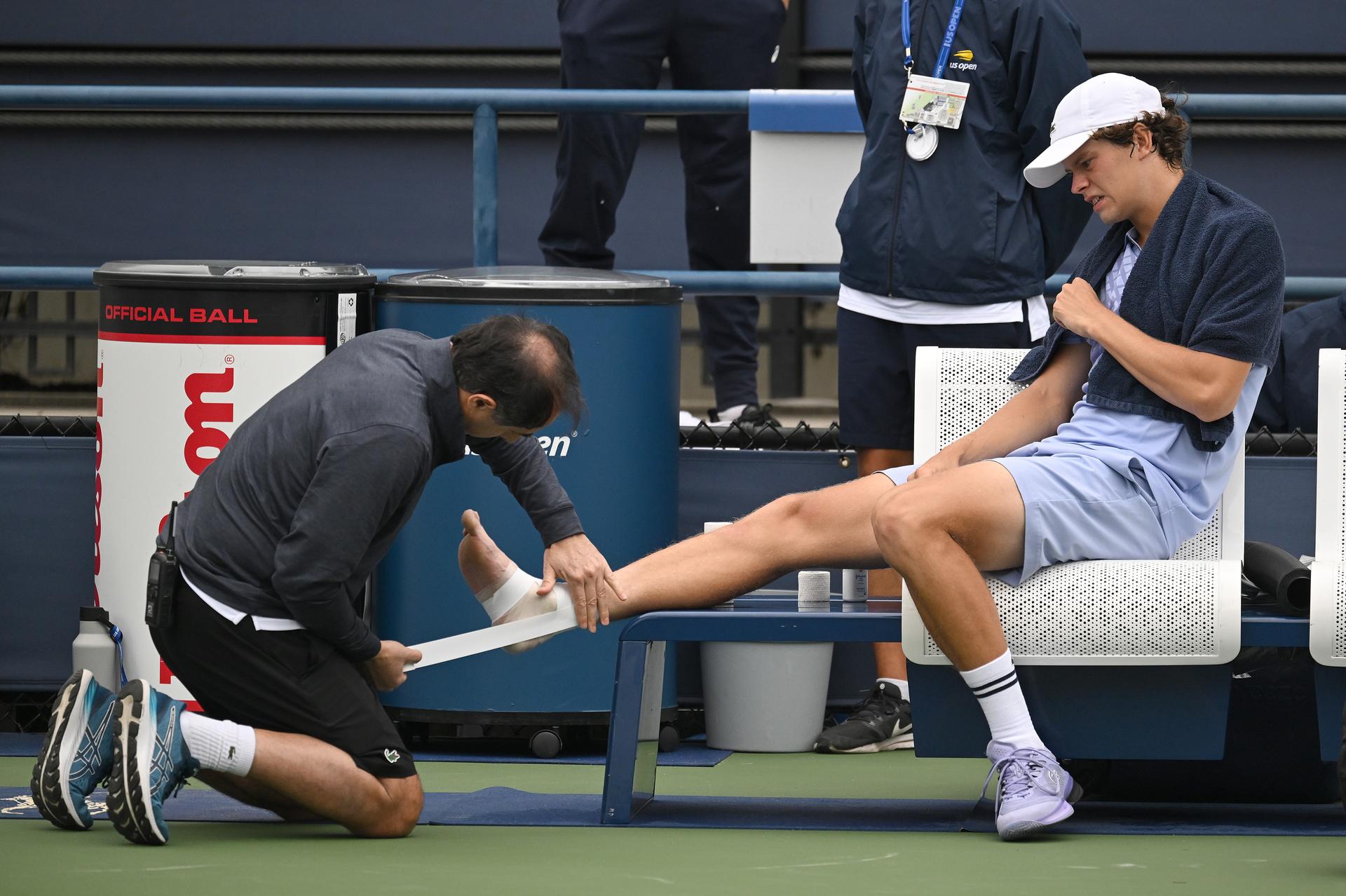 Alexander Blockx of Belgium receives medical attention after suffering an ankle injuring during a tennis match between Belgian Blockx and Belgian Coppejans, in the second round of the qualifications for the men's signles of the 2025 US Open Grand Slam tennis tournament in New York City, USA, Thursday 21 August 2025. BELGA PHOTO TONY BEHAR