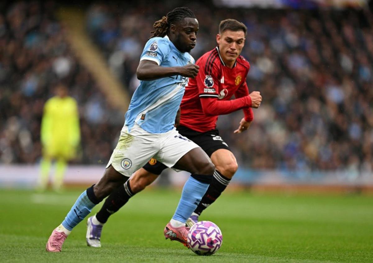Manchester City's Belgian midfielder #11 Jeremy Doku (L) runs with the ball shadowed by Manchester United's Uruguayan midfielder #25 Manuel Ugarte (R) during the English Premier League football match between Manchester City and Manchester United at the Etihad Stadium in Manchester, north west England, on September 14, 2025.  Oli SCARFF / AFP
