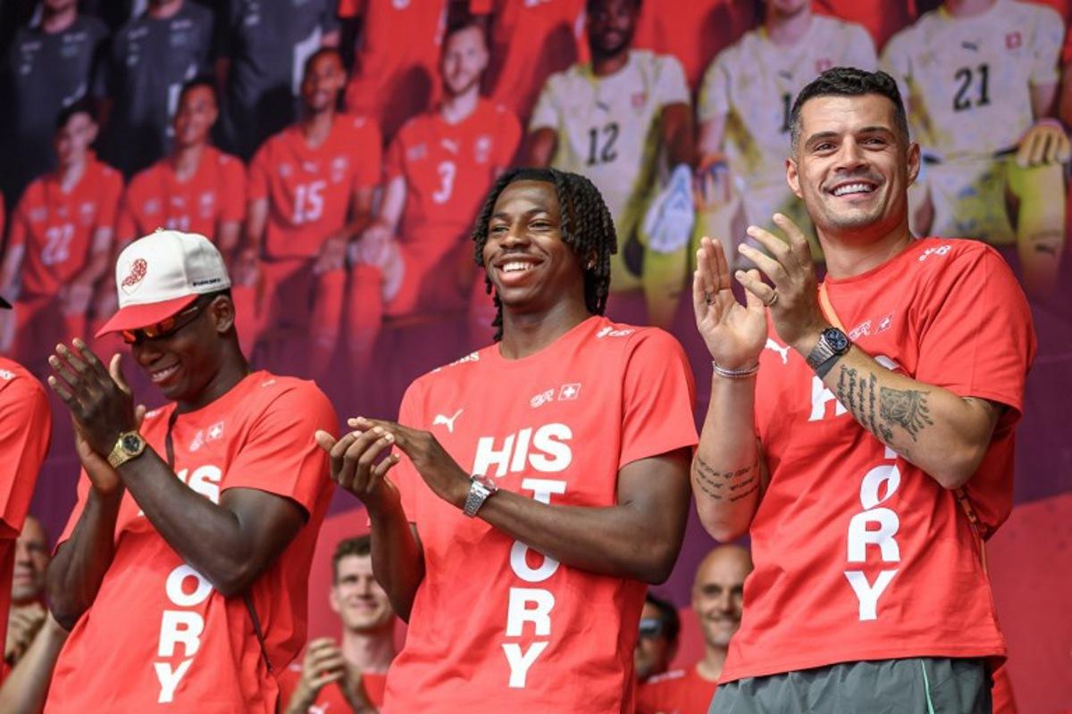 (From L) Switzerland's players forward #07 Breel Embolo, midfielder #09 Johan Manzambi and midfielder #10 Granit Xhaka applaud during a fan reception welcoming the team back to the country following its 2026 FIFA World Cup quarter-final match against Argentina, in Zurich on July 14, 2026.  Fabrice COFFRINI / AFP