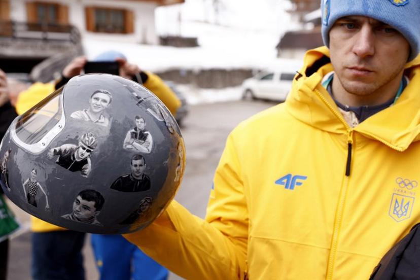 Ukraine's skeleton racer Vladyslav Heraskevych holds his helmet, which depicts victims of his country's war with Russia, in Cortina d'Ampezzo on February 12, 2026. Heraskevych was disqualified from the Winter Olympics on February 12, 2026 after refusing to back down over his banned helmet, which depicts victims of his country's war with Russia. The International Olympic Committee said he had been kicked out of the Milan-Cortina Games "after refusing to adhere to the IOC athlete expression guidelines". Odd ANDERSEN / AFP