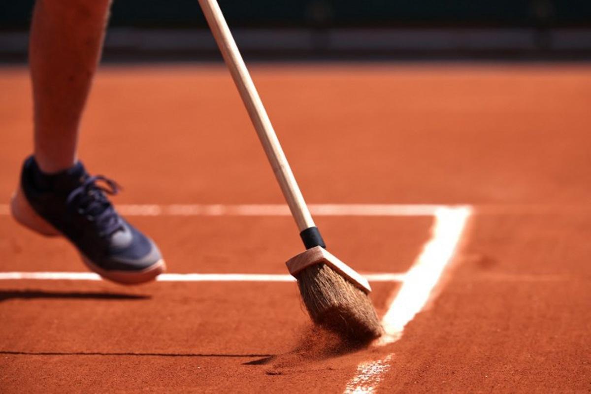 A staff member sweeps the clay on a court during the French Open tennis tournament at the Roland Garros Complex in Paris on May 26, 2024.  Anne-Christine POUJOULAT / AFP