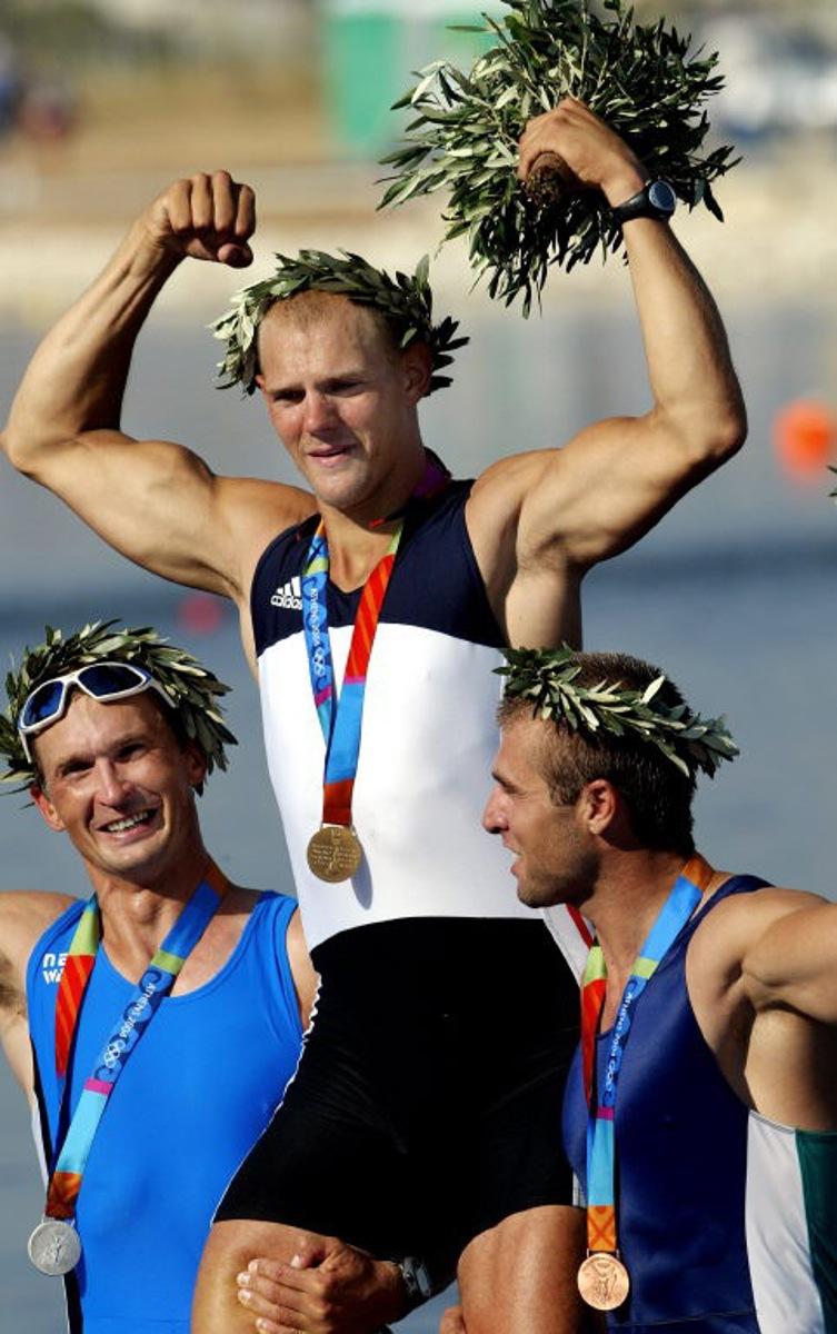 Silver medal from Estonia Jueri Jaanson (L) and bronze medalist from Bulgaria Ivo Yanakiev (R) lift gold medalist Norwegian Olaf Tufte during the medal ceremony for the Men's Single Sculls final for the Athens 2004 Olympic Games at the Schinias Rowing and Canoeing Center, outside Athens, 21 August 2004.     AFP PHOTO / MLADEN ANTONOV  MLADEN ANTONOV / AFP