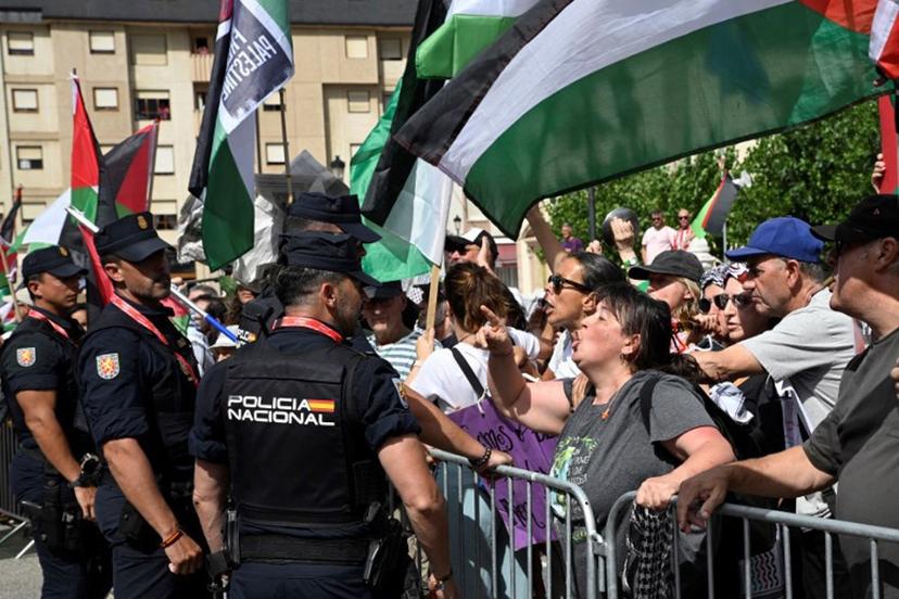 Pro-Palestinian protesters confront police as they wave flags at the start of the 15th stage of the Vuelta a Espana cycling tour, a 167 km race between A Veiga/Vegadeo and Monforte de Lemos, on September 7, 2025.    Miguel RIOPA / AFP