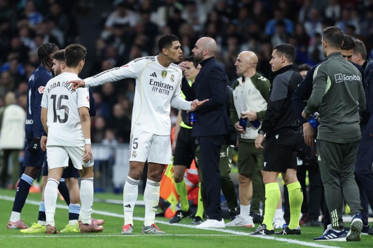 Real Madrid's English midfielder #05 Jude Bellingham (C) argues with an assistant referee after receiving a yellow card during the Spanish league football match between Real Madrid CF and RC Celta de Vigo at the Santiago Bernabeu Stadium in Madrid on December 7, 2025.  Thomas COEX / AFP