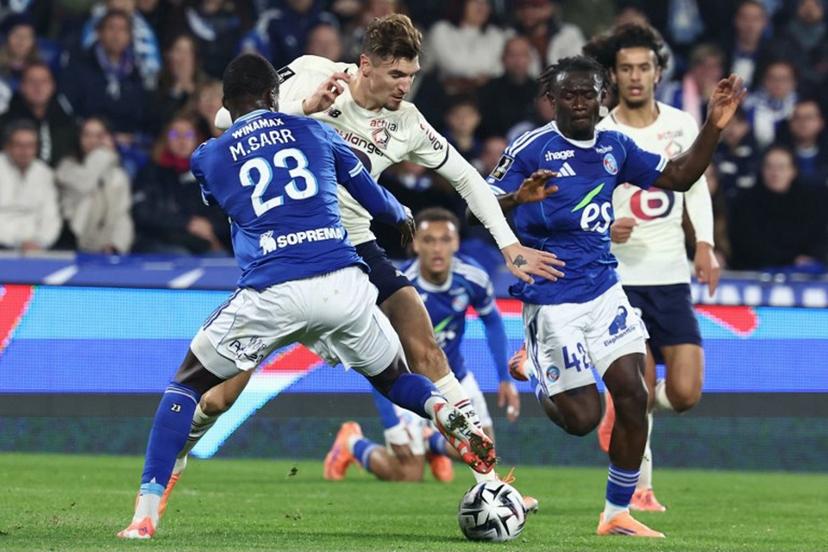 Lille's Belgian defender #12 Thomas Meunier (C) fights for the ball with Strasbourg's French defender #23 Mamadou Sarr during the French L1 football match between RC Strasbourg Alsace and Lille LOSC at the Stade de la Meinau in Strasbourg, eastern France, on November 9, 2025.  Frederick FLORIN / AFP