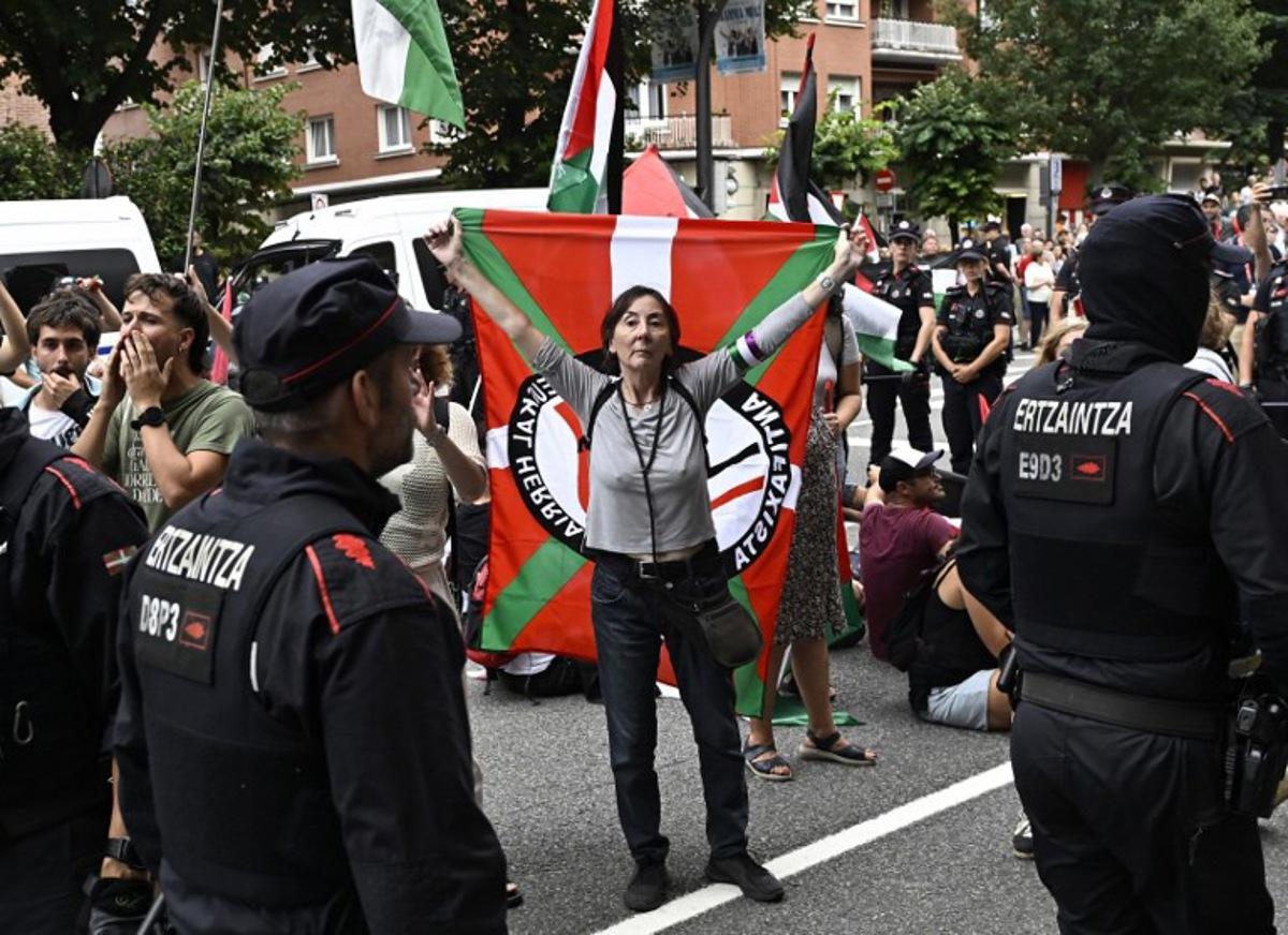 Pro-Palestinian protesters holding Palestinian and Basque flags demonstrate next to Basque regional police 'Ertzaintza' officers, following the Vuelta cycliste race 11th stage, in Bilbao, on September 3, 2025. Pro-Palestinian protest forces Vuelta stage to be shortened and to take the time at 3 kilometres before the line, according to the organisers, AFP reports. ANDER GILLENEA / AFP