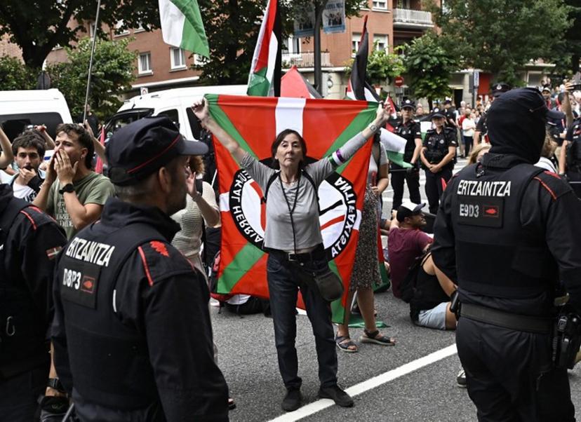 Pro-Palestinian protesters holding Palestinian and Basque flags demonstrate next to Basque regional police 'Ertzaintza' officers, following the Vuelta cycliste race 11th stage, in Bilbao, on September 3, 2025. Pro-Palestinian protest forces Vuelta stage to be shortened and to take the time at 3 kilometres before the line, according to the organisers, AFP reports. ANDER GILLENEA / AFP