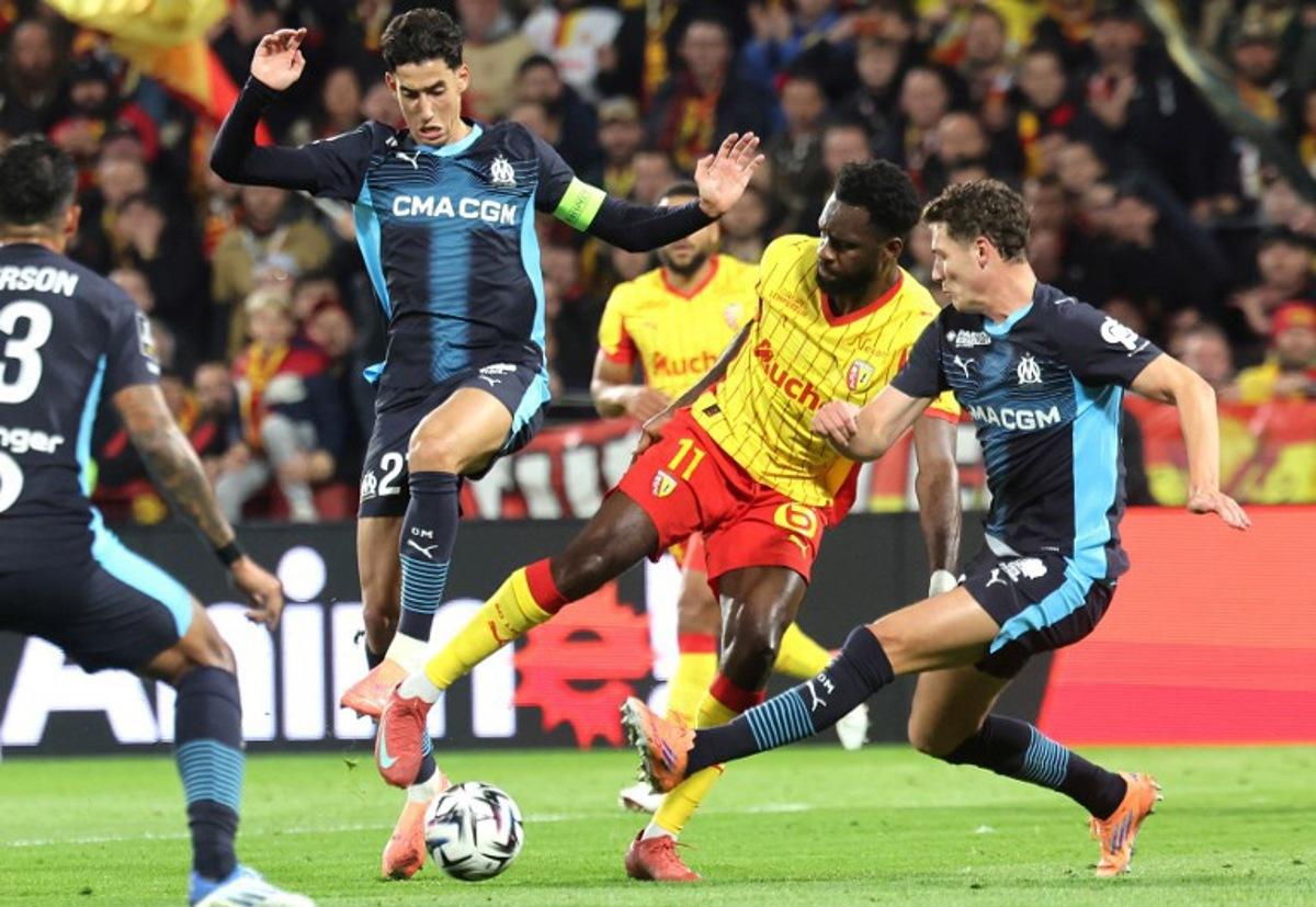 Lens' French forward #11 Odsonne Edouard (CR) fights for the ball with Marseille's Maroccan defender #21 Nayef Aguerd (CL) and Marseille's French defender #28 Benjamin Pavard (R) during the French L1 football match between RC Lens and Olympique de Marseille (OM) at the Stade Bollaert-Delelis in Lens, northern France, on October 25, 2025. Francois LO PRESTI / AFP