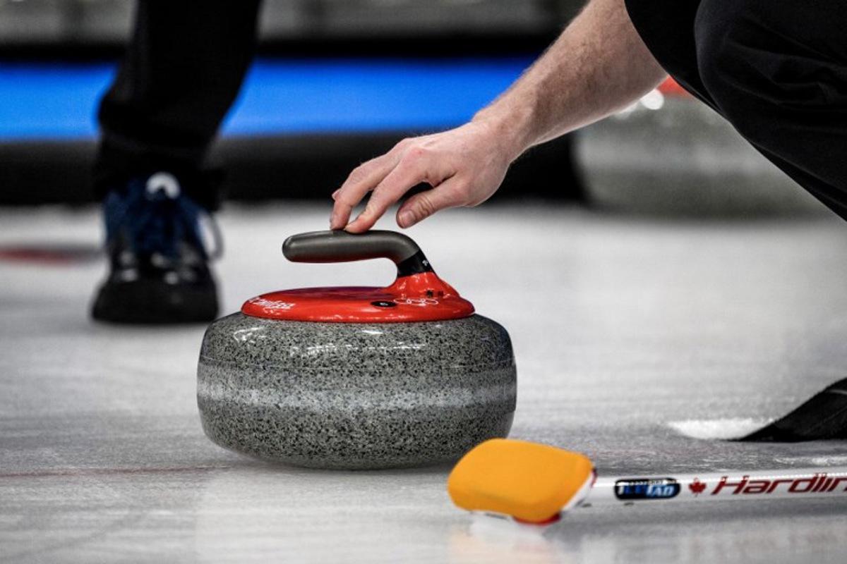 A competitor prepares to curl the stone during the men's bronze medal game of the Beijing 2022 Winter Olympic Games curling competition between Canada and USA at the National Aquatics Centre in Beijing on February 18, 2022. Jeff PACHOUD / AFP