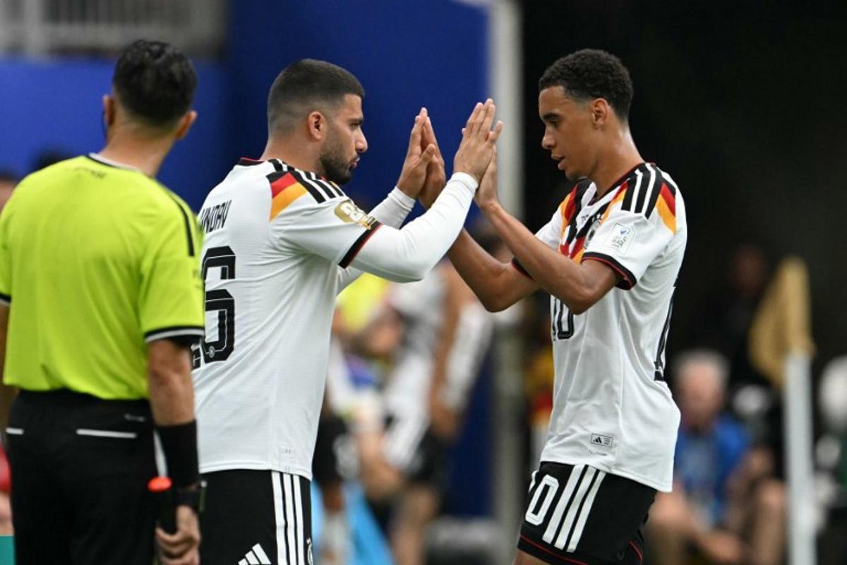 Germany's midfielder #10 Jamal Musiala (R) taps hands with Germany's forward #26 Deniz Undav (L) as he is substituted during the 2026 World Cup Group E football match between Germany and Curacao at the Houston Stadium in Houston on June 14, 2026. RONALDO SCHEMIDT / AFP
