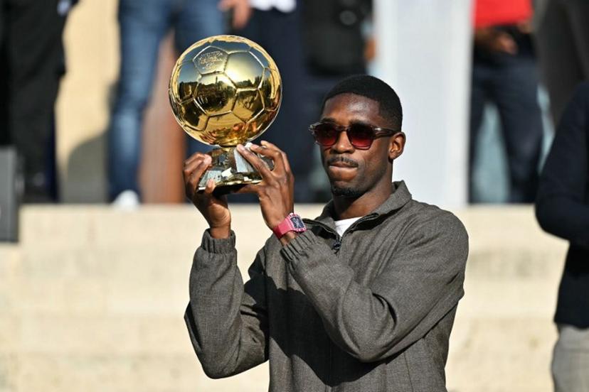 Paris Saint-Germain's French forward and 2025 Ballon d'Or winner Ousmane Dembele displays his trophy during a presentation ceremony at the City Hall in Evreux, his hometown and where he started playing club football, on October 12, 2025. LOU BENOIST / AFP