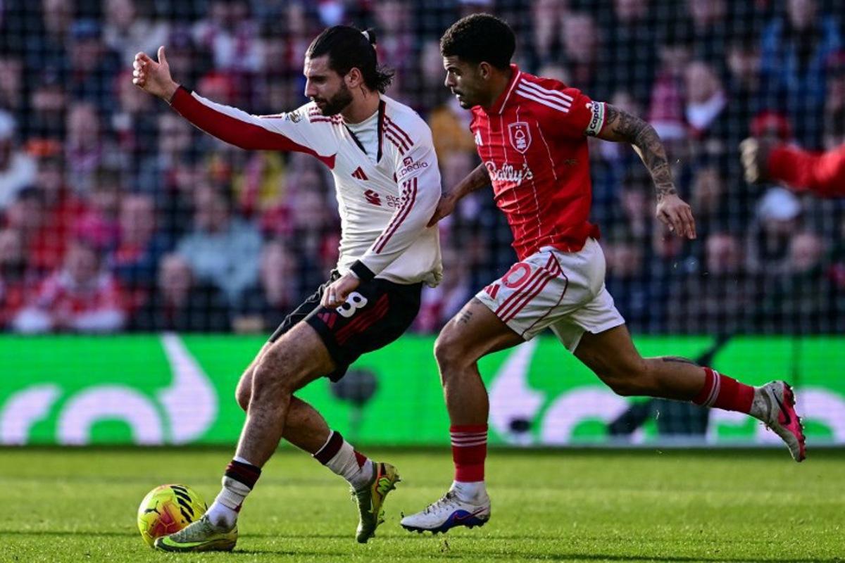 Nottingham Forest's English midfielder #10 Morgan Gibbs-White (R) pulls on the jersey of Liverpool's Hungarian midfielder #08 Dominik Szoboszlai (L) during the English Premier League football match between Nottingham Forest and Liverpool at The City Ground in Nottingham, central England on February 22, 2026. Ben STANSALL / AFP