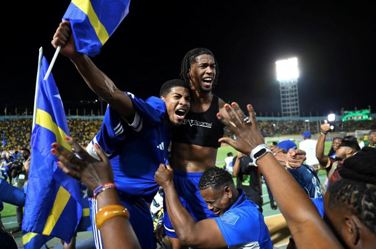 Curaçao players and fans celebrate World Cup 2026 qualification after a 0-0 draw with Jamaica at the National Stadium in Kingston, Jamaica on November 18, 2025. The tiny Caribbean nation of Curacao became the smallest country ever to qualify for the World Cup on November 18 as Haiti booked their return to the tournament for the first time in 52 years along with Panama. A nerve-shredding finale to the CONCACAF qualifying campaign saw Curacao -- with a population of just 156,000 -- squeeze into next year's finals in the United States, Canada and Mexico with a 0-0 draw against Jamaica in Kingston. Ricardo MAKYN / AFP