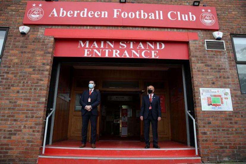 Security guards wearing face masks or covering due to the COVID-19 pandemic, stand at the entrance to Pittodrie Stadium in Aberdeen, northeast Scotland, on August 1, 2020, ahead of the Scottish Premier League football match between Aberdeen and Rangers. Andrew Milligan / AFP / POOL
