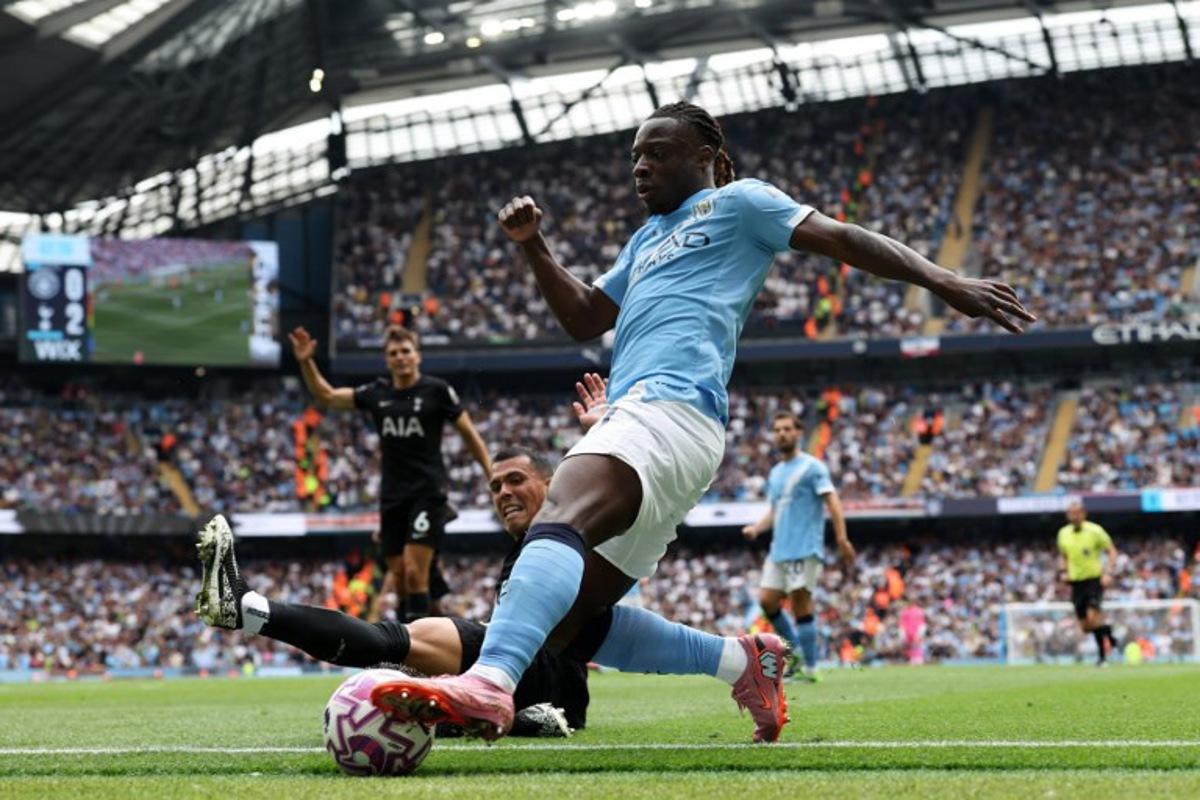 Tottenham Hotspur's Spanish defender #23 Pedro Porro slides in to tackle Manchester City's Belgian midfielder #11 Jeremy Doku during the English Premier League football match between Manchester City and Tottenham Hotspur at the Etihad Stadium in Manchester, north west England, on August 23, 2025. Darren Staples / AFP