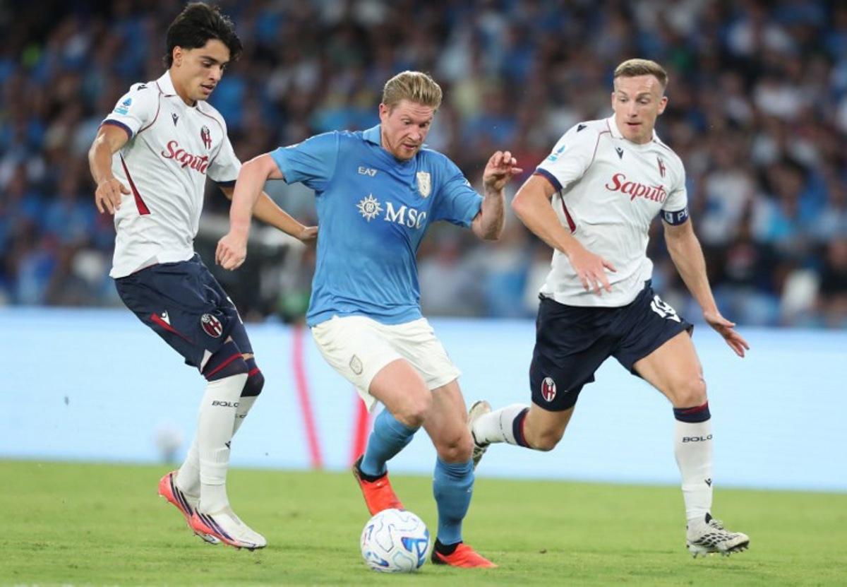 Napoli's Belgian midfielder #11 Kevin De Bruyne (C) fights for the ball with Bologna's Venezuelan midfielder #18 Marco Libra (L) and Bologna's Scottish midfielder #19 Lewis Ferguson (R) during the Italian Serie A football match SSC Napoli vs Bologna FC 1909 at the Diego Armando Maradona Stadium in Naples on September 13, 2026. CARLO HERMANN / AFP