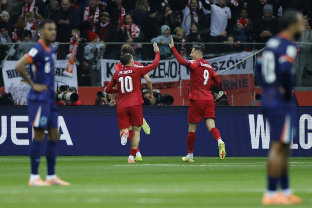 Poland's midfielder #10 Piotr Zielinski (C-L) and Poland's forward #09 Robert Lewandowski (C-R) celebrate after their team scored the opening 1-0 goal during the 1st round - day 9 - Group G World Cup 2026 European Qualifiers football match between Poland and the Netherlands on November 14, 2025 in Warsaw, Poland. Wojtek RADWANSKI / AFP