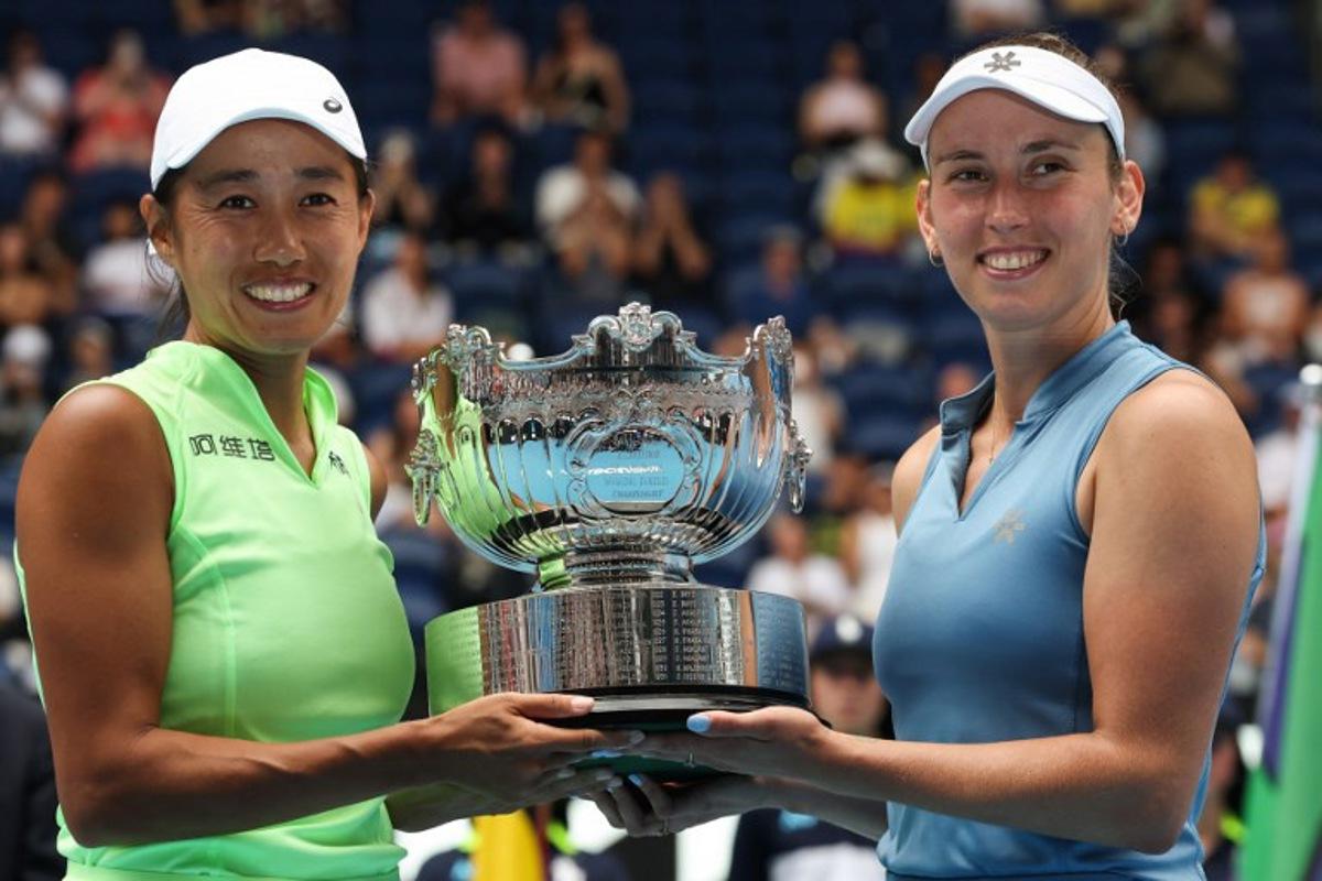 China's Zhang Shuai (L) and partner Belgium's Elise Mertens pose with the winners' trophy after their victory in their women's doubles final match against Kazakhstan's Anna Danilina and Serbia's Aleksandra Krunic on day fourteen of the Australian Open tennis tournament in Melbourne on January 31, 2026. DAVID GRAY / AFP