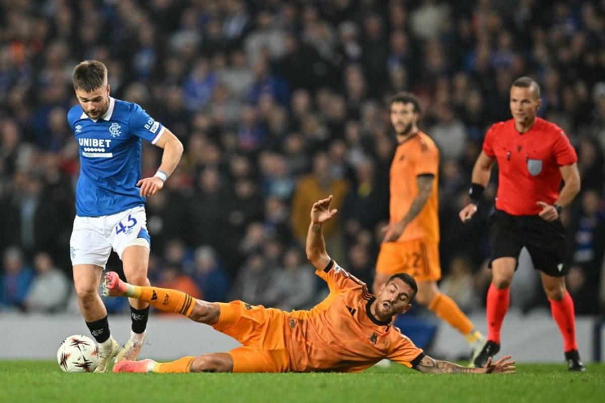 Roma's Italian midfielder #07 Lorenzo Pellegrini (R) goes down in a challenge with Rangers' Belgian midfielder #43 Nicolas Raskin (L) during the UEFA Europa League league-stage football match between Rangers and Roma at Ibrox Stadium in Glasgow on November 6, 2025. ANDY BUCHANAN / AFP