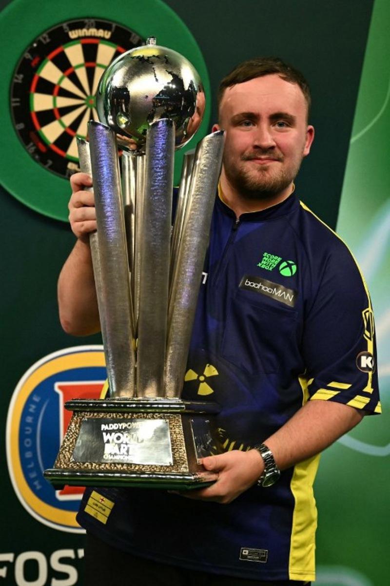 England's Luke Littler poses with the Sid Waddell Trophy after victory over Netherlands' Michael van Gerwen in the PDC World Darts Championship final, at Alexandra Palace in London on January 3, 2025. Luke Littler became darts' youngest world champion at just 17 after thrashing three-time winner Michael van Gerwen in front of an adoring home crowd at London's Alexandra Palace on Friday. This time there was no stopping "Luke the Nuke" as he stormed past Dutchman Van Gerwen by seven sets to three. Ben STANSALL / AFP