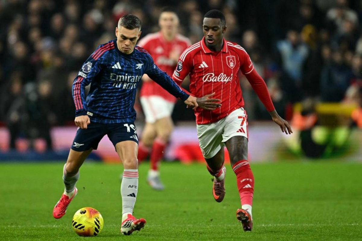 Arsenal's Belgian midfielder #19 Leandro Trossard runs with the ball whilst under pressure from Nottingham Forest's English midfielder #07 Callum Hudson-Odoi during the English Premier League football match between Nottingham Forest and Arsenal at The City Ground in Nottingham, central England, on January 17, 2026. JUSTIN TALLIS / AFP