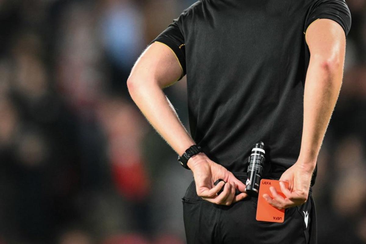 Referee Daniel Siebert puts back in his pocket the red card after showing it to Napoli's Italian forward #27 Lorenzo Lucca during the UEFA Champions League, league phase football match between PSV Eindhoven and Napoli at the Philips Stadium, in Eindhoven, on October 21, 2025. NICOLAS TUCAT / AFP