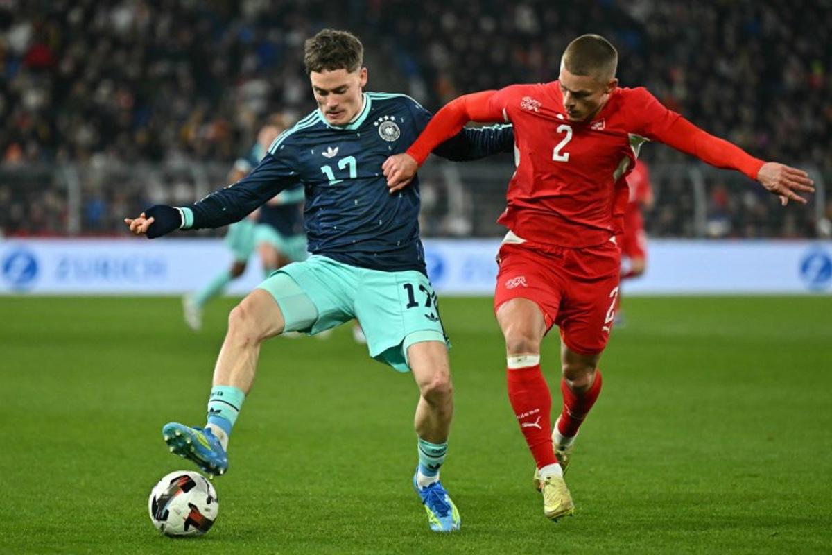 Germany's midfielder #17 Florian Wirtz fights for the ball with Switzerland's defender #2 Miro Muheim during the international friendly football match between Switzerland and Germany at St. Jakob-Park in Basel, Switzerland on March 27, 2026. Fabrice COFFRINI / AFP